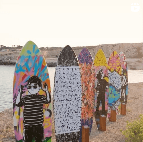 Planches de surf exposées lors d’une collaboration artistique entre Arpe et d’autres artistes